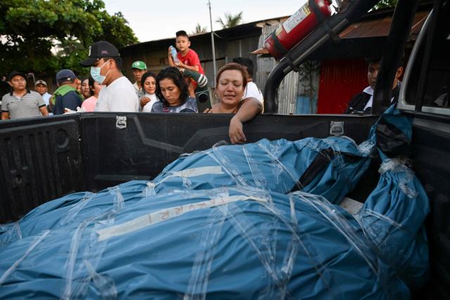 A woman reacts in front of some of the bodies of victims from the wreckage of a vessel involved in an accident at the port of Iparia, outside the Manantay morgue in Pucallpa, in the Ucayali department of Peru’s central jungle, on December 1, 2025. At least 12 people, including three children, died when a landslide buried two boats docked at a river port in central Peru, with dozens of others missing, officials said. (Photo by Hugo Alejos / AFP)