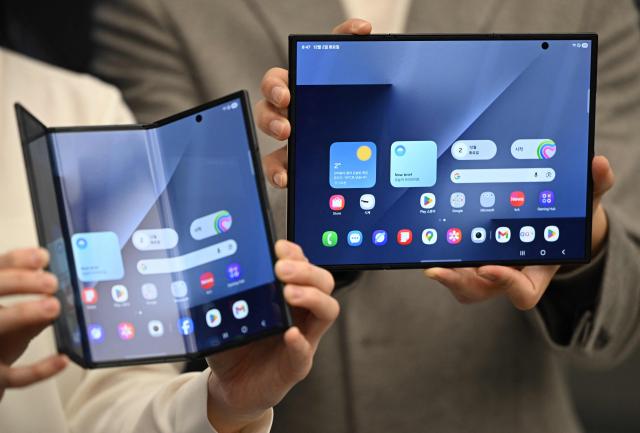 Promoters show Samsung Galaxy Z TriFold smartphones during a launch event at a Samsung store in Seoul on December 2, 2025. Samsung Electronics unveiled its first tri-fold phone on December 2, as the conglomerate rushes to show it can keep pace with rivals in generative AI. (Photo by Jung Yeon-je / AFP)