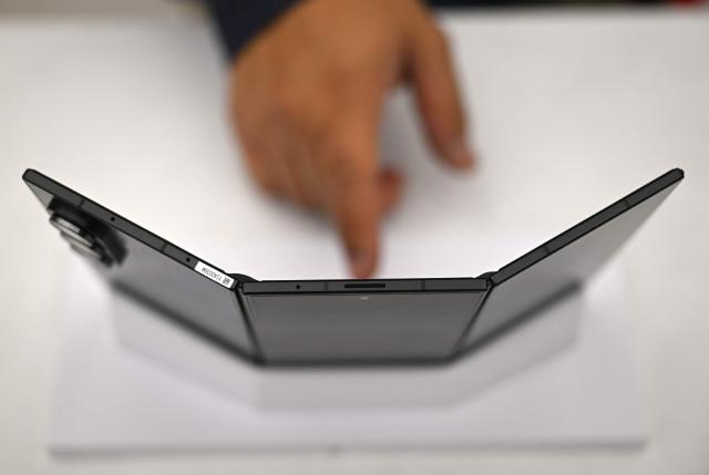 TOPSHOT - A visitor touches a Samsung Galaxy Z TriFold smartphone during a launch event at a Samsung store in Seoul on December 2, 2025. Samsung Electronics unveiled its first tri-fold phone on December 2, as the conglomerate rushes to show it can keep pace with rivals in generative AI. (Photo by Jung Yeon-je / AFP)