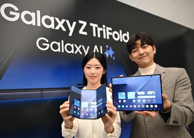 Promoters show Samsung Galaxy Z TriFold smartphones during a launch event at a Samsung store in Seoul on December 2, 2025. Samsung Electronics unveiled its first tri-fold phone on December 2, as the conglomerate rushes to show it can keep pace with rivals in generative AI. (Photo by Jung Yeon-je / AFP)