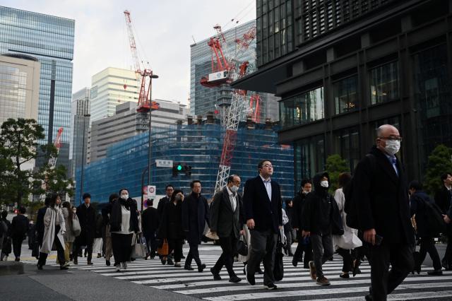 Office workers cross a road near Tokyo station in Tokyo on December 2, 2025. (Photo by GREG BAKER / AFP)