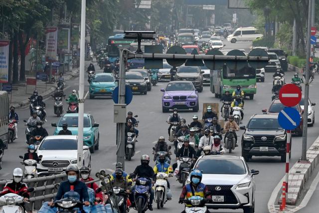 Motorists make their way on a street during heavy air pollution conditions in Hanoi on December 2, 2025. (Photo by Nhac NGUYEN / AFP)