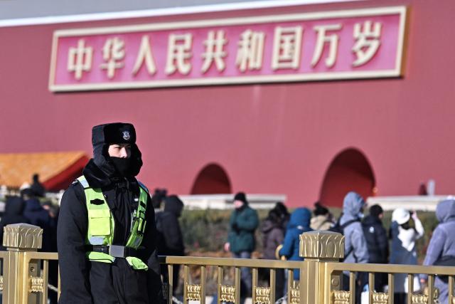 A security personnel stands guard at Tiananmen Square in Beijing on December 2, 2025. (Photo by Pedro PARDO / AFP)