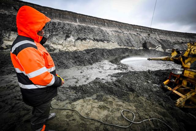 A worker looks at a water gun operating in Kaliningrad Amber Combine quarry in the village of Yantarny (former German Palmniken), some 40 kms from Kaliningrad on October 16, 2025. The Russian enclave of Kaliningrad, former German Koenigsberg, about half the size of Belgium, is separated from the rest of Russia by Poland and Lithuania. Founded in 1255, once the home of the kings of Prussia and forever associated with the 18th-century philosopher Immanuel Kant, Kaliningrad is home to around one million people comprising 80 nationalities, although the Russian community (80 percent) is by far the largest. The territory's effective separation from Russia dates back to the break-up of the Soviet Union in 1991. As a key military installation on the Baltic, the city and the port were closed off to non-Soviet citizens until 1991. In 1992 it became a free-trade zone, and in 1996 a special economic zone, acquiring privileges with relation to foreign investors. The enclave retains its strategic importance, both as the port for Russian missile-equipped submarines and as a base for the 11th army. The Kaliningrad Amber Combine produces 90% of the world's amber. (Photo by Alexander NEMENOV / AFP)