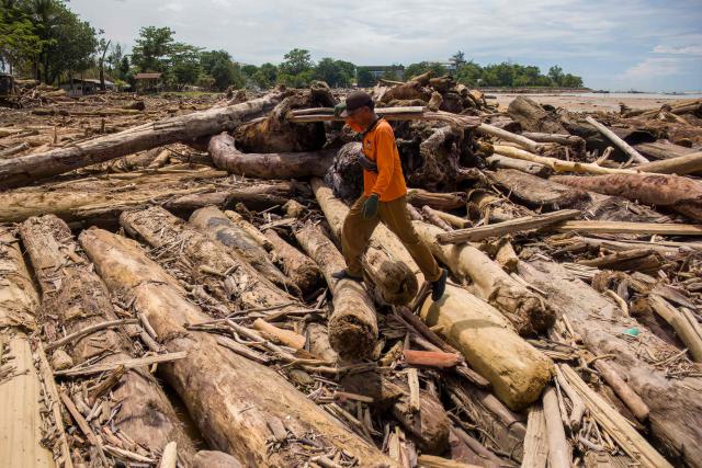 Environmental agency workers clean up piles of logs washed ashore on Padang beach, West Sumatra, on December 2, 2025, after being swept along by the flash floods that struck the region. Governments and aid groups in Indonesia and Sri Lanka worked to rush aid December 2 to hundreds of thousands stranded by deadly flooding that has killed around 1,200 people in four countries. (Photo by REZAN SOLEH / AFP)