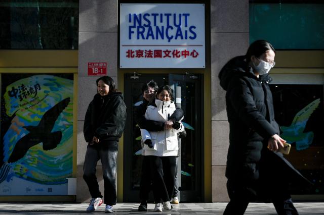 A group of people walk out of the Institut Francais in Beijing on December 2, 2025. (Photo by WANG Zhao / AFP)