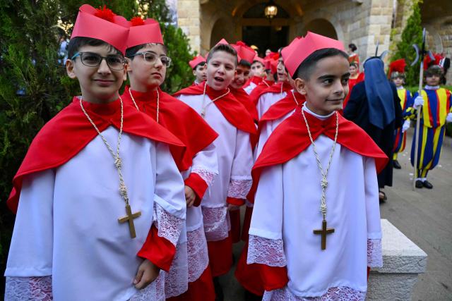 Children dressed as cardinals are pictured outside the Sisters of the Cross Hospital in Beirut's northern suburb of Jdeideh before the visit of Pope Leo XIV on December 2, 2025.  (Photo by Andreas SOLARO / AFP)
