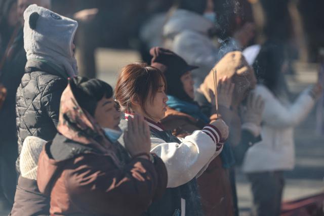 People burn incense and pray at the Lama Temple in Beijing on December 2, 2025. (Photo by Ludovic MARIN / AFP)
