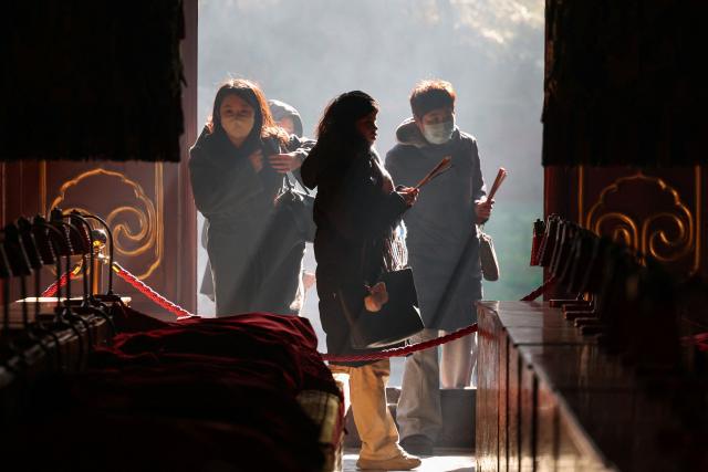 People burn incense and pray at the Lama Temple in Beijing on December 2, 2025. (Photo by Ludovic MARIN / AFP)