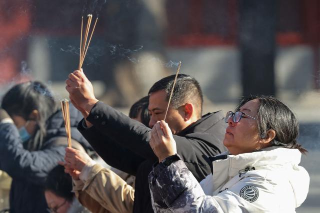 People burn incense and pray at the Lama Temple in Beijing on December 2, 2025. (Photo by Ludovic MARIN / AFP)