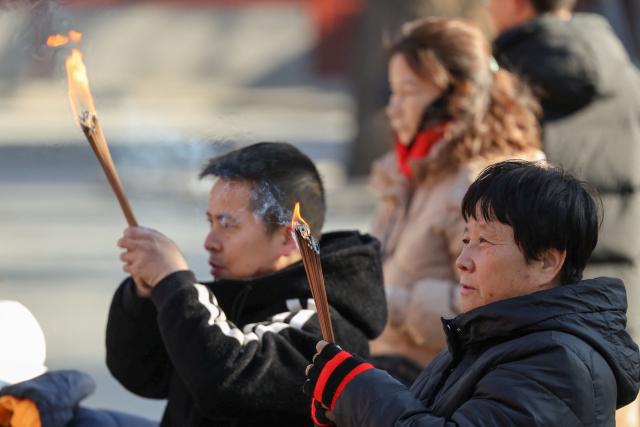 People burn incense and pray at the Lama Temple in Beijing on December 2, 2025. (Photo by Ludovic MARIN / AFP)
