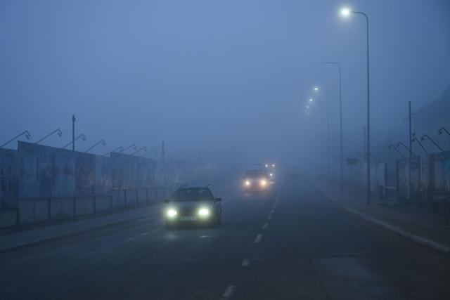 Motorists drive on a road in thick smog near Pristina on December 2, 2025. (Photo by Armend NIMANI / AFP)