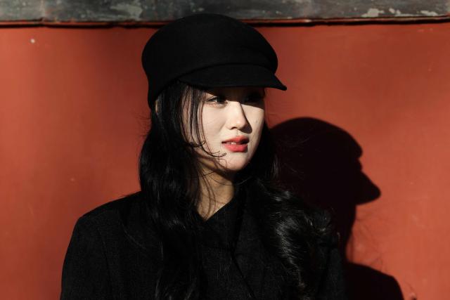 A woman poses for pictures on a street in Beijing on December 2, 2025. (Photo by Ludovic MARIN / AFP)