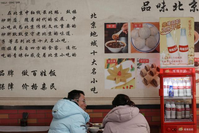 A couple sits for a meal at a restaurant in Beijing on December 2, 2025. (Photo by Ludovic MARIN / AFP)