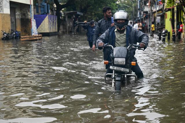 A commuter wades through flood induced by Cyclone Ditwah in Chennai on December 2, 2025. (Photo by R. Satish BABU / AFP)