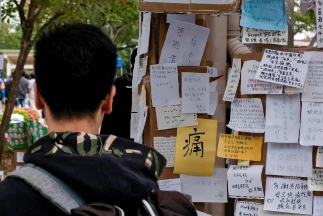 A man looks at messages placed by mourners at a makeshift memorial outside the Wang Fuk Court apartment blocks in the aftermath of the deadly November 26 fire in Hong Kong's Tai Po district on December 2, 2025. Hong Kong's leader announced on December 2 the creation of a judge-led "independent committee" to investigate the devastating fire at an apartment complex that killed 151 people last week. Authorities have said the blaze, which was the city's worst fire in decades, spread quickly via netting used on exterior scaffolding that fell short of fire-resistance standards and failed to stop flames from spreading. (Photo by Tommy WANG / AFP)