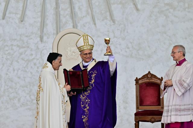 Pope Leo XIV (C) receives a chalice as he leads a mass at Beirut's waterfront on December 2, 2025. Tens of thousands of people gathered at Beirut's waterfront as Pope Leo XIV held mass in the morning of December 2, the highlight of the Catholic leader's visit to the capital. (Photo by Giuseppe CACACE / AFP)