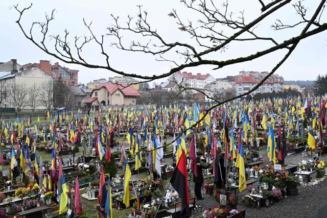 Two women stand among the graves of fallen Ukrainian soldiers as they visit the Lychakiv military cemetery in Lviv on December 2, 2025, amid the Russian invasion of Ukraine. (Photo by Sergei GAPON / AFP)
