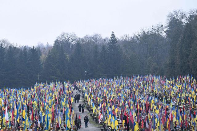 Mourners leave among the graves of fallen Ukrainian soldiers folowing a funeral ceremony for Ukrainian servicemen Marian Maksymiv and Andriy Dobryansky at the Lychakiv military cemetery in Lviv on December 2, 2025, amid the Russian invasion of Ukraine. (Photo by Sergei GAPON / AFP)