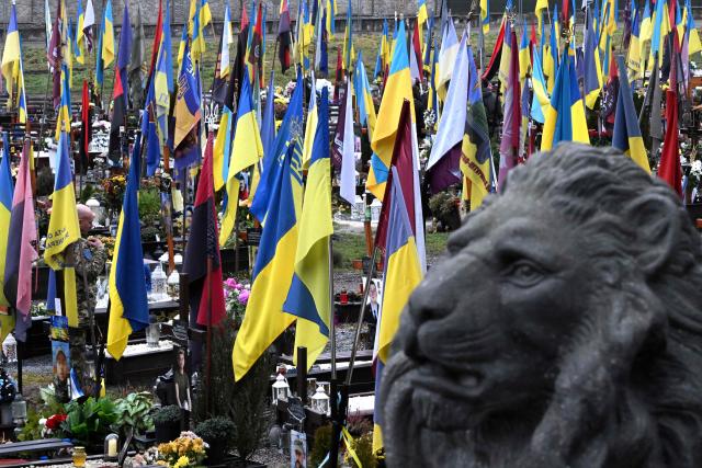 A Ukrainian soldier makes the sign of the cross in front of the graves of fallen Ukrainian soldiers as he visits the Lychakiv military cemetery in Lviv on December 2, 2025, amid the Russian invasion of Ukraine. (Photo by Sergei GAPON / AFP)