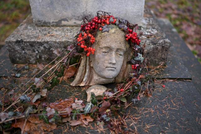 A fragment of a damaged sculpture lies on the gravestone at the Lychakiv cemetery in Lviv on December 2, 2025, amid the Russian invasion of Ukraine. (Photo by Sergei GAPON / AFP)