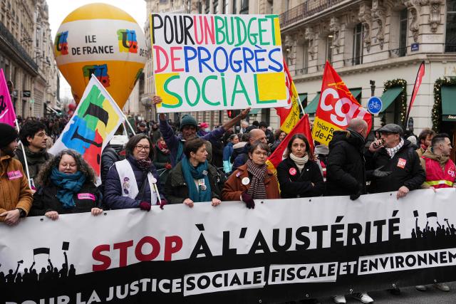 French trade union General Confederation of Labour (CGT) secretary general Sophie Binet (C) looks on flanked by protesters as they stand behind a banner reading "Stop austerity -
for a social, fiscal and environmental justice" and take part in a demonstration as part of a call by trade unions for strikes and demonstrations for higher wages and against austerity, in Paris on December 2, 2025. (Photo by Dimitar DILKOFF / AFP)