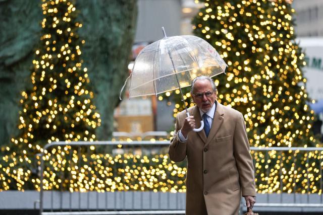A man carries an umbrella in the rain as he walks past holiday decorations in Midtown Manhattan in New York City on December 2, 2025. (Photo by TIMOTHY A. CLARY / AFP)