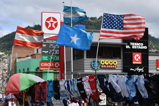 The flags of the United States and of Honduras flutter alongside the flags of the National Party (C) -which candidate was Nasry Asfura- and of the Liberal Party (L) -which candidate was Salvador Nasralla- at a street atall in Tegucigalpa on December 2, 2025, two days after the national election. Donald Trump accused election officials in Honduras on Monday of "trying to change" their presidential election outcome, as a partial digital tally revealed the two frontrunners are locked in a "technical tie." (Photo by Orlando SIERRA / AFP)