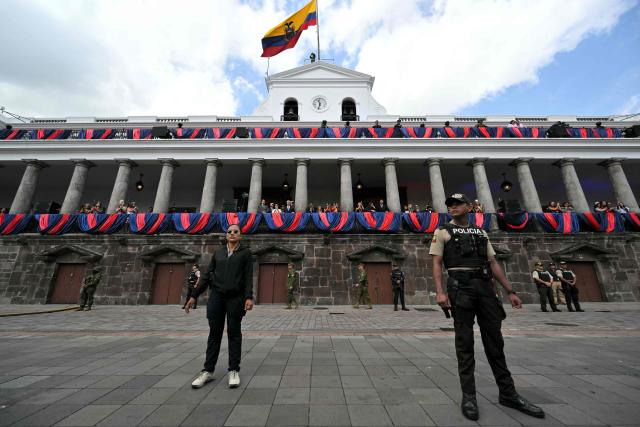 Soldiers and policemen stand guard outside the Carondelet Palace during a traditional serenade in Quito on December 2, 2025, on the Ecuadorian capital's founding anniversary. (Photo by Rodrigo BUENDIA / AFP)