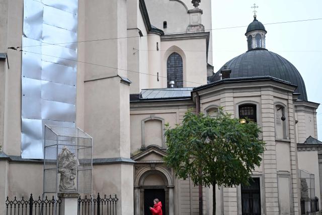 This photograph shows metal plates covering the windows of the Latin Cathedral and a protective structure encasing a sculpture of an Apostle to protect against possible damage caused by air strikes, in Lviv on December 2, 2025, amid the Russian invasion of Ukraine. (Photo by Sergei GAPON / AFP)