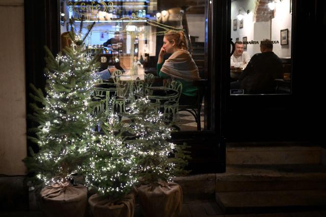People sit in a cafe decorated for Christmas in Lviv on December 2, 2025, amid the Russian invasion of Ukraine. (Photo by Sergei GAPON / AFP)