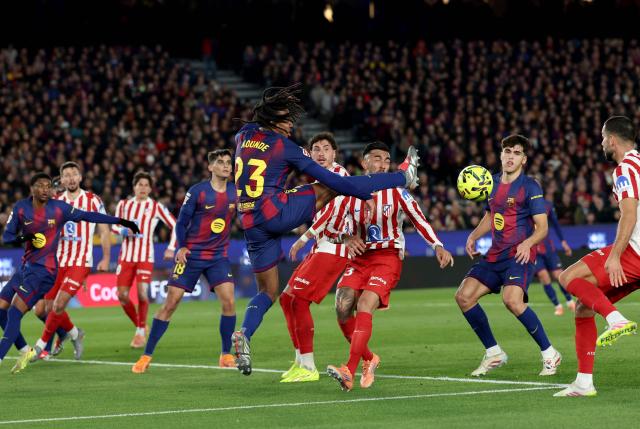 Barcelona's French defender #23 Jules Kounde jumps and kicks the ball during the Spanish league football match between FC Barcelona and Club Atletico de Madrid at Camp Nou Stadium in Barcelona on December 2, 2025. (Photo by Lluis GENE / AFP)