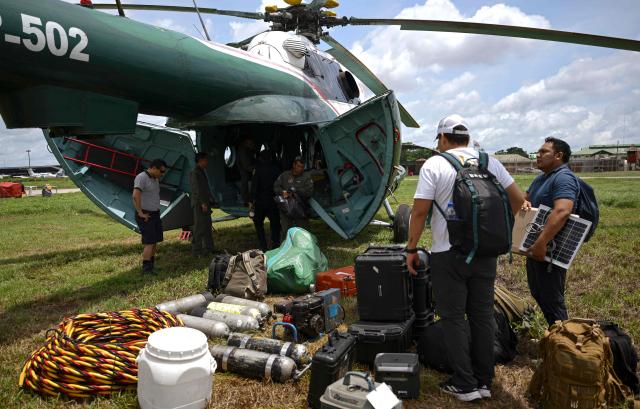 Police officers prepare the gear to work on the area of a vessel accident at the port of Iparia, in the Ucayali department in Peru's central jungle, on December 2, 2025. At least 12 people, including three children, died when a landslide buried two boats docked at a river port in central Peru, with dozens of others missing, officials said. (Photo by Hugo Alejos / AFP)