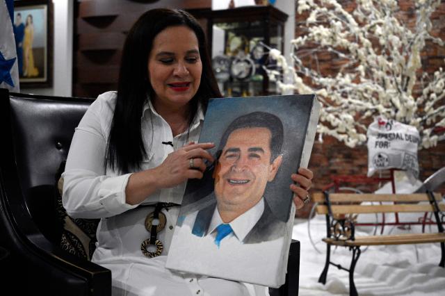 Ana Garcia de Hernandez, wife of former Honduras President Juan Orlando Hernandez, holds a painting of her husband during an interview with AFP in Tegucigalpa on December 2, 2025. Fallen from grace with his former ally, the United States, which sentenced him to 45 years in prison last year, Juan Orlando Hernandez left prison on December 1 amid strong pressure from President Donald Trump over Honduras' presidential elections. (Photo by Orlando SIERRA / AFP)