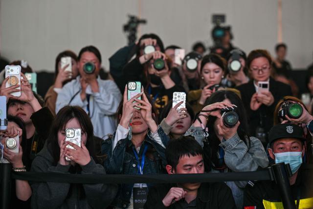 This picture taken on November 13, 2025 shows fans, influencers and media personnel attending the presentation of Rokid glasses in Hangzhou, in China's eastern Zhejiang province. In China, AI glasses let the wearer pay in shops with just a glance at a QR code and a voice command, as a growing number of companies look to conquer both growing domestic and overseas markets. Interest in smart eyewear is soaring worldwide after more than a decade of stalled promise, with advances in artificial intelligence sparking renewed interest in the sector. (Photo by Hector RETAMAL / AFP) / To go with 'CHINA-TECHNOLOGY-WEARABLES-AI, FOCUS' by Emily WANG