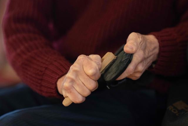 A ballroom dancer uses a wire brush on the suede soles of his partner's dancing shoes before taking part in a Tea Dance, in the Main Ballroom of Liverpool Town Hall, in Liverpool, north west England on November 17, 2025. Tea dance, which evolved from the tradition of afternoon tea in the late 19th century, is enjoying a revival, especially since the pandemic. One recent chilly Monday afternoon in the northwest city of Liverpool, 115 dancers paid £12 to waltz, tango and cha-cha-cha under the chandeliers of the stunning 18th century town hall. Refreshments included tea and cakes. (Photo by Oli SCARFF / AFP)