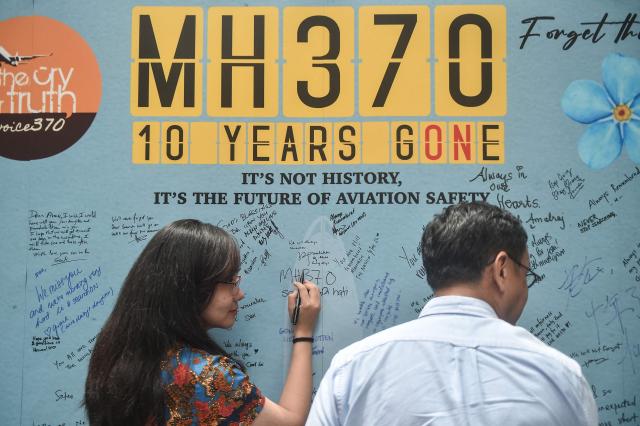 (FILES) A woman writes a message during an event held by relatives of missing passengers and supporters to mark the 10th anniversary of the disappearance of Malaysia Airlines flight MH370, in Subang Jaya on March 3, 2024. The search for missing Malaysia Airlines flight MH370 will resume at the end of December, Malaysia's transport ministry said on December 3, 2025, more than a decade after the plane disappeared. (Photo by Arif Kartono / AFP)