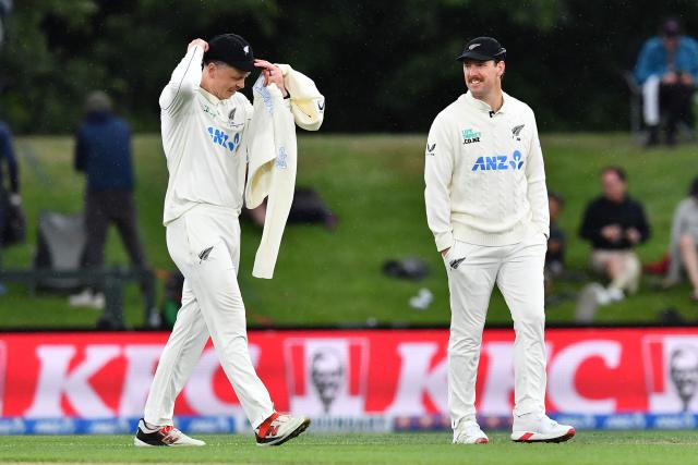 New Zealand's Matt Henry (R) and Michael Bracewell leave the field as rain falls during day two of the first Test cricket match between New Zealand and West Indies at Hagley Oval in Christchurch on December 3, 2025. (Photo by Sanka Vidanagama / AFP)