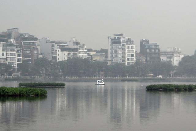 People make their way on a swan-shaped pedal boat across Truc Bach Lake amid heavy air pollution conditions in Hanoi on November 3, 2025. (Photo by Nhac NGUYEN / AFP)