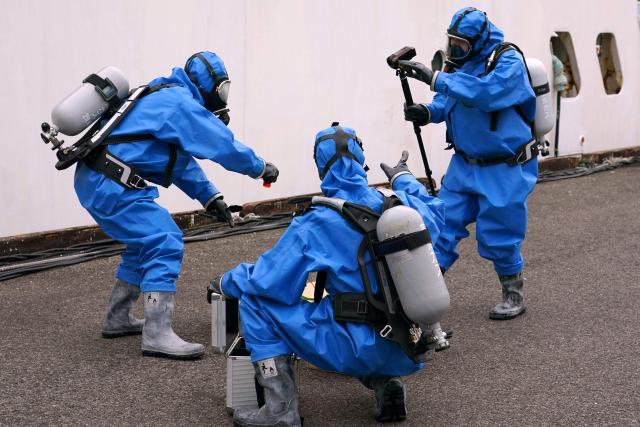 Police officers in protective gear discover a suspicious substance in the cargo during the PSI (Proliferation Security Initiative) maritime interdiction exercise Pacific "Shield 25" as part of the training at a port in Tokyo on December 3, 2025. (Photo by Kazuhiro NOGI / AFP)