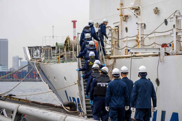 Officials from the Japan Coast Guard, customs, and police board the suspicious ship to inspect its cargo during the PSI (Proliferation Security Initiative) maritime interdiction exercise Pacific "Shield 25" as part of the training at a port in Tokyo on December 3, 2025. (Photo by Kazuhiro NOGI / AFP)