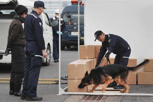 A sniffer dog from customs searches for suspicious substances in the cargo during the PSI (Proliferation Security Initiative) maritime interdiction exercise Pacific "Shield 25" as part of the training at a port in Tokyo on December 3, 2025. (Photo by Kazuhiro NOGI / AFP)