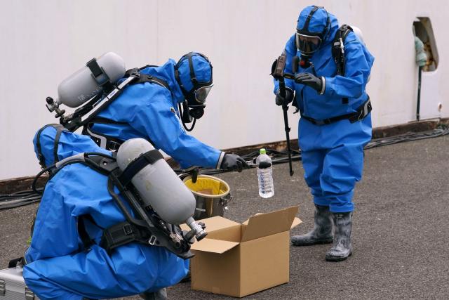 Police officers in protective gear discover a suspicious substance in the cargo during the PSI (Proliferation Security Initiative) maritime interdiction exercise Pacific "Shield 25" as part of the training at a port in Tokyo on December 3, 2025. (Photo by Kazuhiro NOGI / AFP)