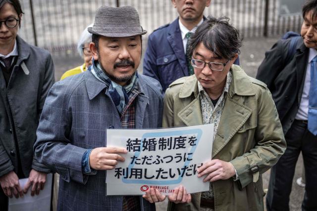 Campaigners holding placard reading 'We just want marriage to be normal' speak to the media outside the Supreme Court in Tokyo on December 3, 2025. (Photo by Yuichi YAMAZAKI / AFP)