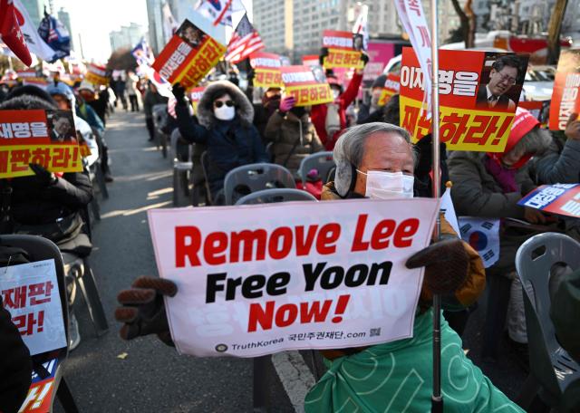 Supporters of South Korea's ousted president Yoon Suk Yeol hold a placard reading "Remove Lee, Free Yoon now!" during a rally marking the first anniversary of Yoon's declaration of martial law, in front of the National Assembly in Seoul on December 3, 2025. (Photo by Jung Yeon-je / AFP)