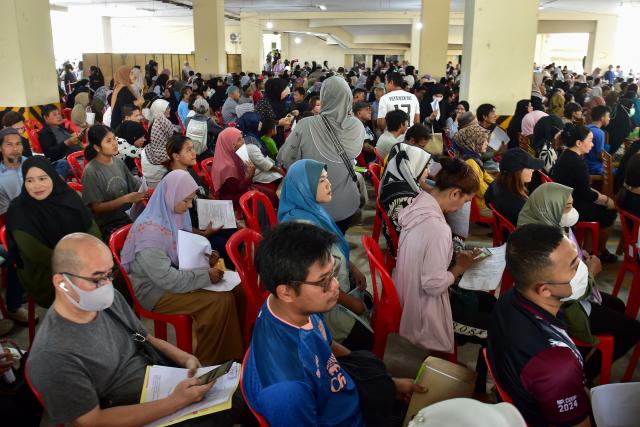 Flood victims wait to register to receive disaster relief funds at the Narathiwat municipality building in Thailand's southern province of Narathiwat on December 3, 2025, after severe flooding affected thousands of people in the region. Heavy rains in the annual monsoon season, exacerbated by a tropical storm in the region, inundated parts of southern Thailand in late November, killing dozens and trapping many in their homes. (Photo by Madaree TOHLALA / AFP)