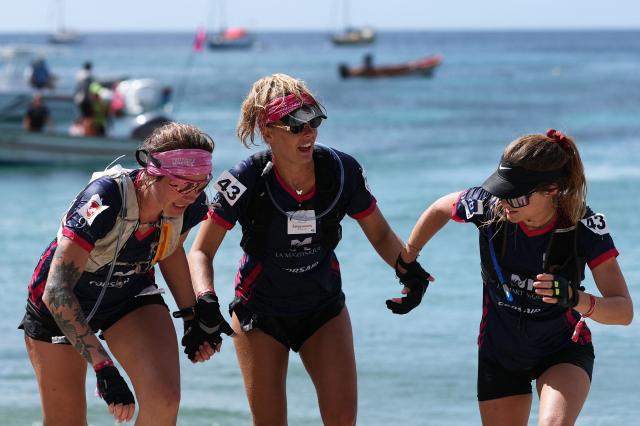 (From L) Team All Amazones' Laura Payelle, Alexandra Elize and Louana Roy run to cross the finish line on the French Caribbean island of Martinique to win the "Raid des Alizes", an exclusively all-female multi sport competition on November 29, 2025. The all-female event features running, mountain biking, kayaking, and trekking events with each team representing a charity project of their choice with the overall ranking determining the prize money which will be directly donated to the charities. (Photo by Anne-Christine POUJOULAT / AFP)