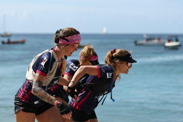 (From L) Team All Amazones' Laura Payelle, Alexandra Elize and Louana Roy run to cross the finish line on the French Caribbean island of Martinique to win the "Raid des Alizes", an exclusively all-female multi sport competition on November 29, 2025. The all-female event features running, mountain biking, kayaking, and trekking events with each team representing a charity project of their choice with the overall ranking determining the prize money which will be directly donated to the charities. (Photo by Anne-Christine POUJOULAT / AFP)