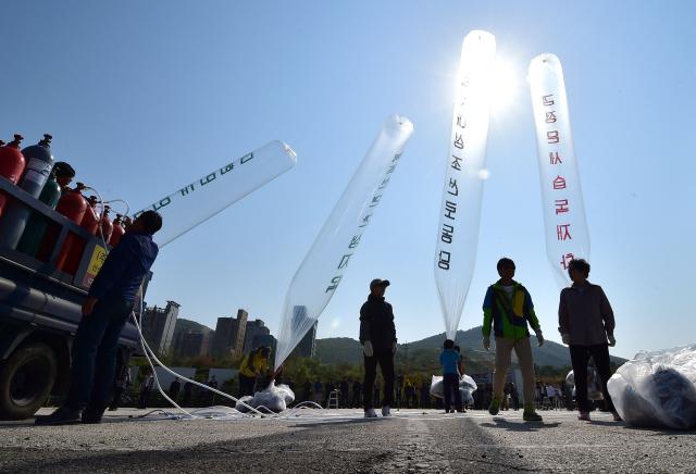 (FILES) South Korean activists prepare to release balloons carrying anti-North Korea leaflets at a park near the inter-Korea border in Paju, north of Seoul on October 10, 2014. South Korea has passed a law banning unmanned balloons from no-fly zones, Seoul's unification ministry said December 3, 2025, in a move expected to curb activists from flying anti-Pyongyang leaflets across the border. (Photo by Jung Yeon-je / AFP)