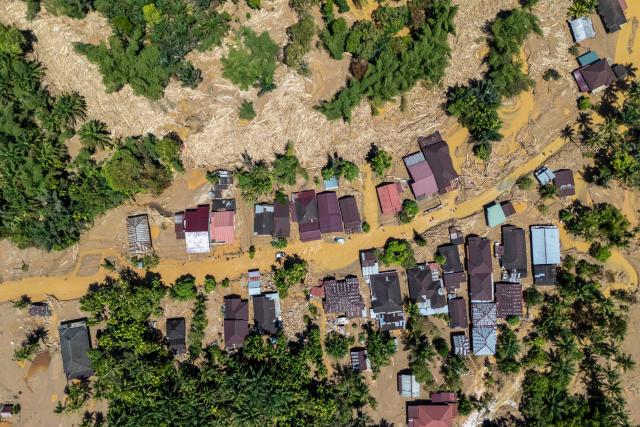 This picture shows an aerial view of villagers wading through the mudflow to find a shelter in the aftermath of flash floods in Tukka village, Central Tapanuli, North Sumatra province, on December 3, 2025. Officials in Indonesia and Sri Lanka battled on December 3 to reach survivors of deadly flooding in remote, cut-off regions as the toll in the disaster that hit four countries topped 1,300. In Indonesia, there is growing frustration among survivors of catastrophic flooding and landslides over the pace of the rescue effort and aid delivery. (Photo by YT Hariono / AFP)